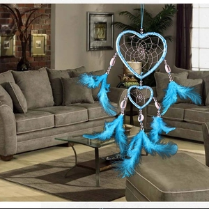 Blue heart-shaped dream catcher with feathers and shells hanging in a modern living room