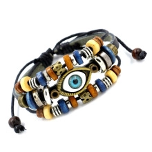 Detailed view of handmade braided leather bracelet featuring evil eye bead and metal charms