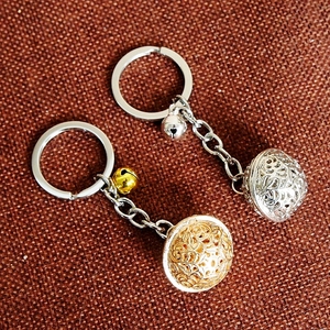 Detail of hollow spherical metal keychains with mini bells in gold and silver finish