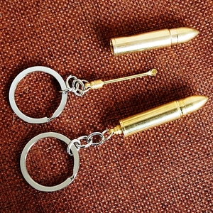 Detailed macro view of two gold bullet keychains featuring a hidden small metal spoon