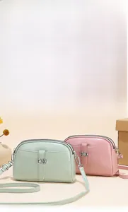Detail van mini crossbodytassen met dubbele ritsen en decoratieve metalen strikjes