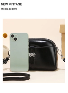 Kleine zwarte halfronde crossbodytas naast een telefoon om het compacte formaat te tonen