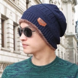 Close-up of deep blue knitted beanie with brown leather patch on an outdoor model