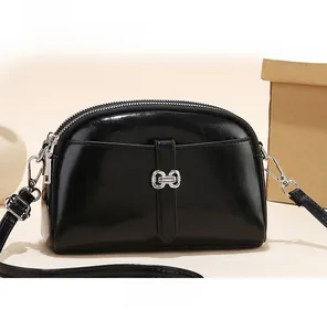 Vooraanzicht van de mini zwarte laklederen crossbodytas met drie ritscompartimenten