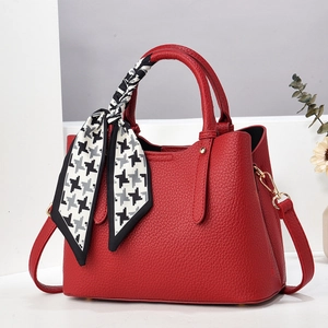 Detail of red pebbled tote with houndstooth scarf and golden metal hardware hooks