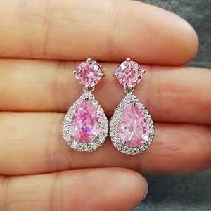 Macro shot of pink teardrop zircon earrings with silver setting held by hand