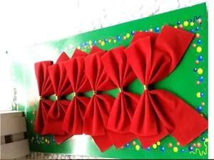 Detail of red velvet Christmas bows with gold ties set on green card for holiday tree decor