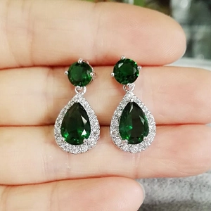 Detail of hand-held emerald green pear-cut drop earrings with sparkling halo zircon stones