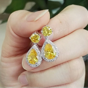 Macro shot of silver drop earrings featuring yellow pear-cut zircon with halo diamonds