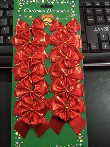 Twelve red metallic fabric Christmas bows neatly arranged on a green display card