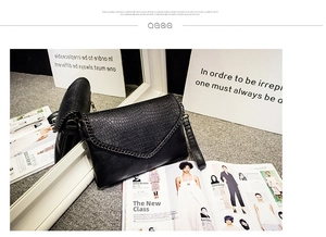 Détail du sac enveloppe noir à motif crocodile avec bordure en chaîne métallique