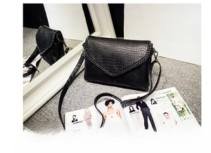 Détail du sac enveloppe noir à motif crocodile avec garniture de chaîne en métal chic
