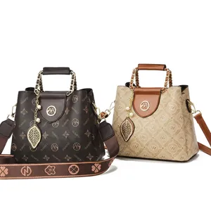 Detail of monogrammed crossbody bags with woven handles and leaf pendants for women