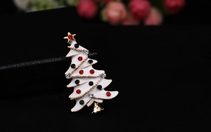 Close-up of white enamel Christmas tree brooch with colorful rhinestones on black leather