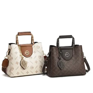 Detail view of stylish crossbody bags in cream and coffee with gold chain handles