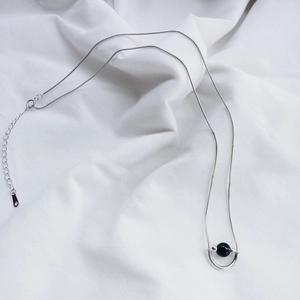 Detail of 925 sterling silver necklace with black onyx bead on white fabric backdrop