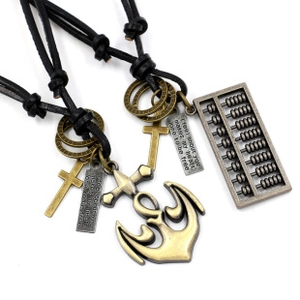 Detail of vintage bronze cross and anchor pendants on black braided leather necklaces