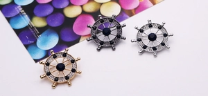 Detail of three helm brooches in gold, silver, and black with blue crystals and rhinestones