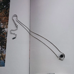 Macro detail of 925 sterling silver snake chain necklace with black onyx pendant on a book