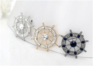 Detail of nautical rudder lapel pins with rhinestones in gold, silver, and dark finishes
