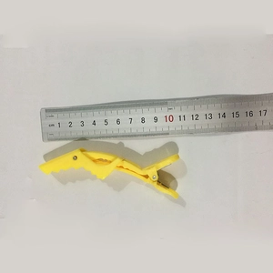 Measurement of a 10cm yellow plastic alligator hair clip with a ruler for size scale