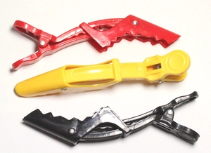 Close-up of red, yellow and black professional alligator hair clips for styling