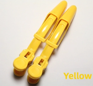 Detail of two professional yellow alligator hair clips with strong spring mechanism