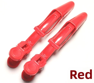 Macro shot of two red plastic sectioning hair clips for salon styling and coloring