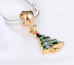 Macro shot of green and red enamel Christmas tree pendant with gold large hole bead charm