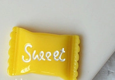Macro view of yellow resin candy accessory featuring white Sweet text engraving