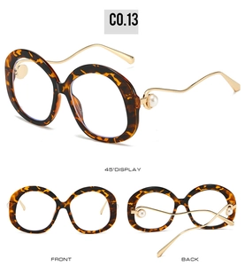 Detail view of tortoiseshell oval sunglasses with pearl accents and wavy gold metal temples