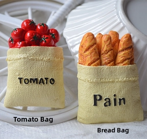 Close-up of resin tomato and baguette magnets with realistic burlap bag texture