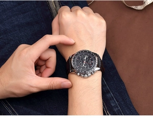 Men's sports watch with black leather strap and luminous dial on wrist