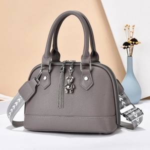 Close-up of grey litchi texture handbag with silver bear charm and tassel details