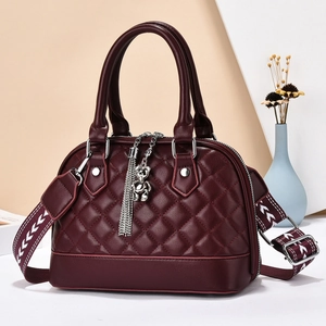 Close-up of wine red quilted handbag with silver bear charm and wide floral strap