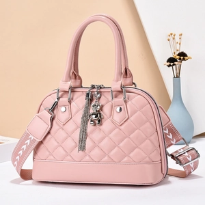 Pink quilted leather handbag with macaron stitching and wide woven strap on white pedestal