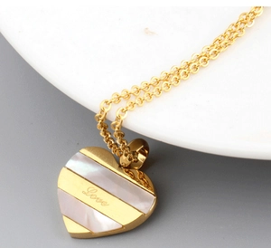 Detail of heart pendant showing white shell inlay with Love engraving on gold steel