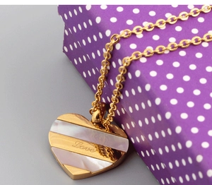 Close-up of heart pendant with shell inlay and Love engraving on a purple gift box