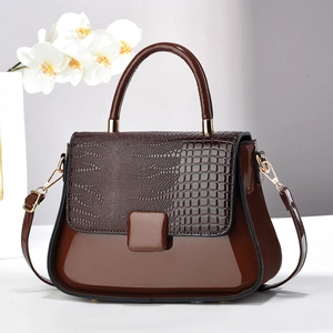 Detail of dark brown faux crocodile leather texture and glossy finish on handbag