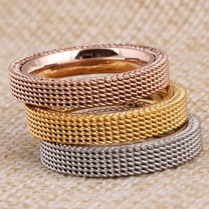 Macro shot of 4mm three-color mesh textured stainless steel rings on a beige linen fabric