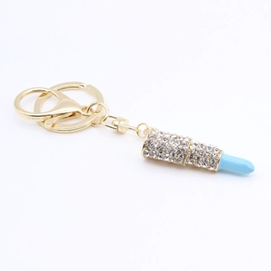 Detailed macro shot of a golden lipstick keychain with blue tip and sparkling rhinestones