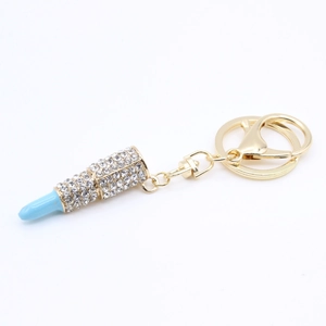 Detailed macro view of gold lipstick keychain with blue top and clear rhinestone inlay