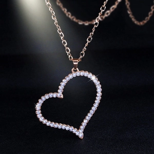 Macro shot of rose gold heart pendant with crystal pavé on black textured fabric