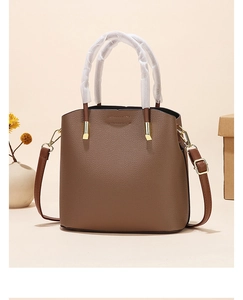 Detail of dark brown lychee leather tote bag with gold hardware and shoulder strap