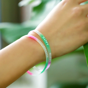 Nahaufnahme von Silikonarmbändern mit Happy und Success Text an einem Handgelenk