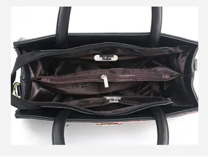 Détail intérieur du grand sac noir montrant les compartiments zippés et la doublure brune