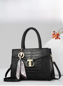 Détail d'un sac à main noir motif crocodile avec fermoir doré et foulard en soie élégant