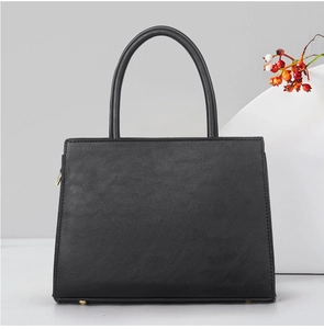 Détail du sac à main en cuir mat noir avec clous de fond dorés et poignée élégante