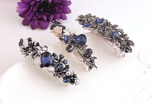 Detail of vintage silver hair clips with blue crystals and pearls on white surface