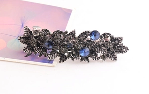 Close-up of vintage hair clip featuring dark blue rhinestones and floral alloy patterns